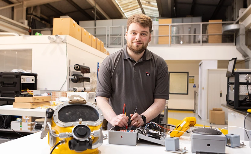 Smiling young man working on electrical equipment in an industrial workshop