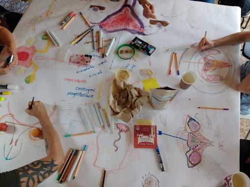 Colourful crayon and marker drawings of uteruses on an A0 paper