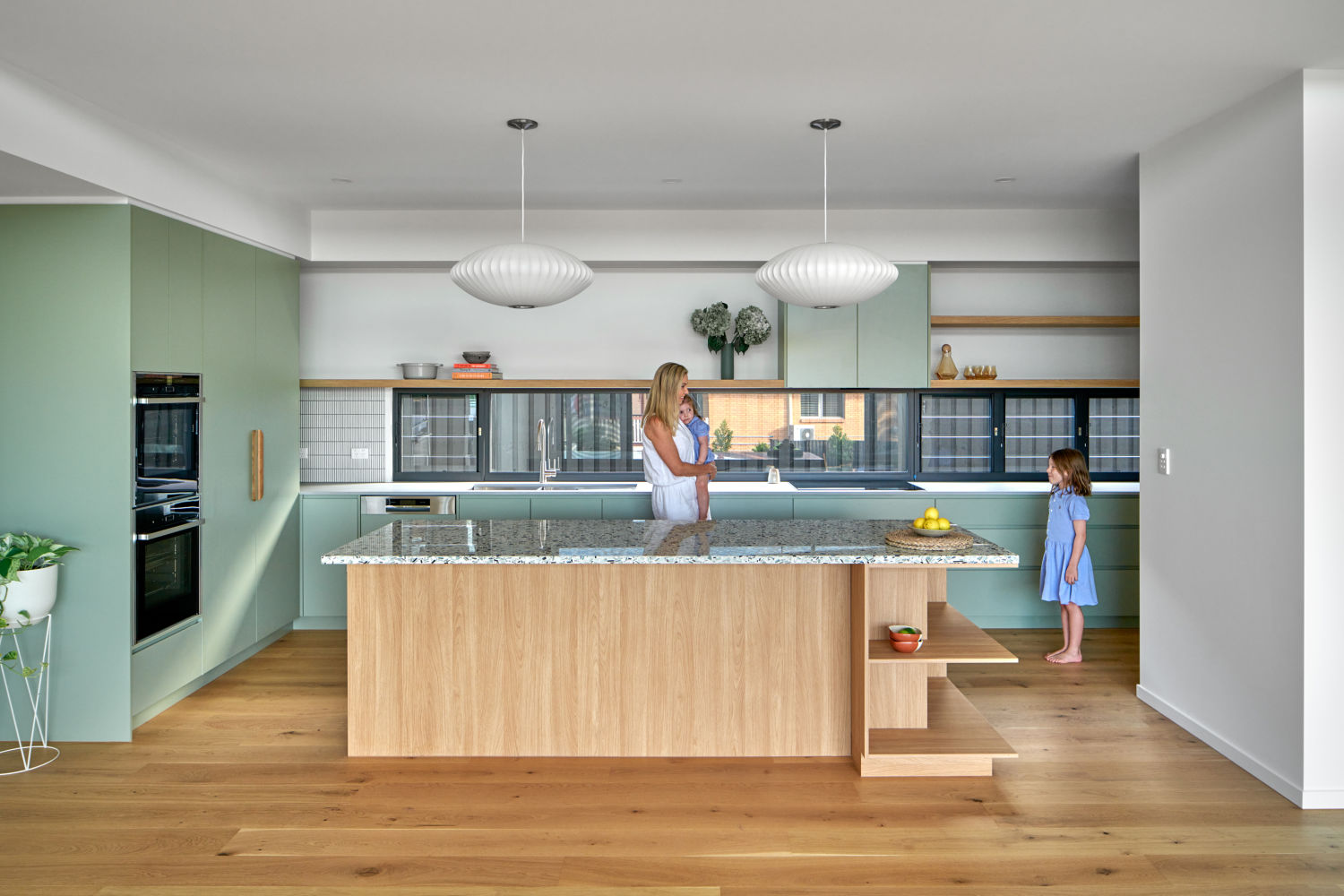 The suite of finishes echoes the clean Modernist styling, with hints of timber amongst crisp splashes of colours throughout the joinery, informed by the cool tones of recycled glass featured in the kitchen benchtop.