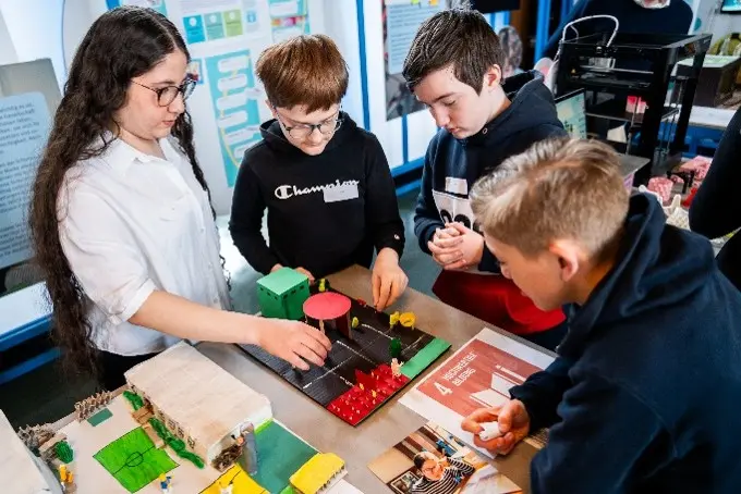 Kinder stehen um ein Spiel und lernen Technik kreativ kennen