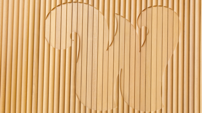 The letter "W" in wavy font on a textured wooden wall.