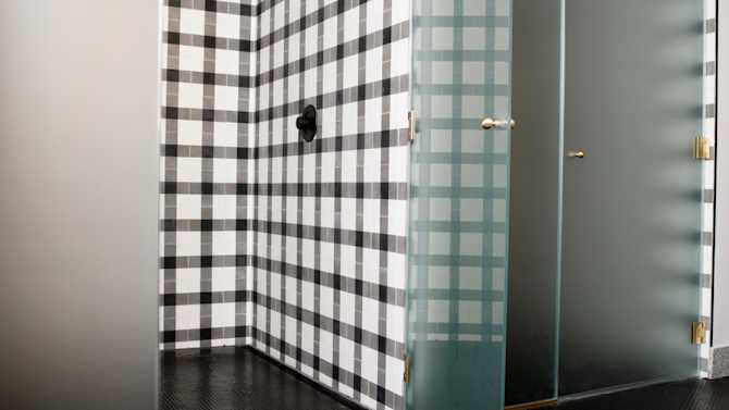 Two spacious showers with black and white tile and frosted glass doors.