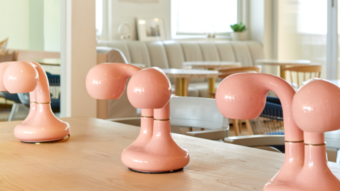 Desk with retro pink lights on top of it and a couch and chairs in the background.