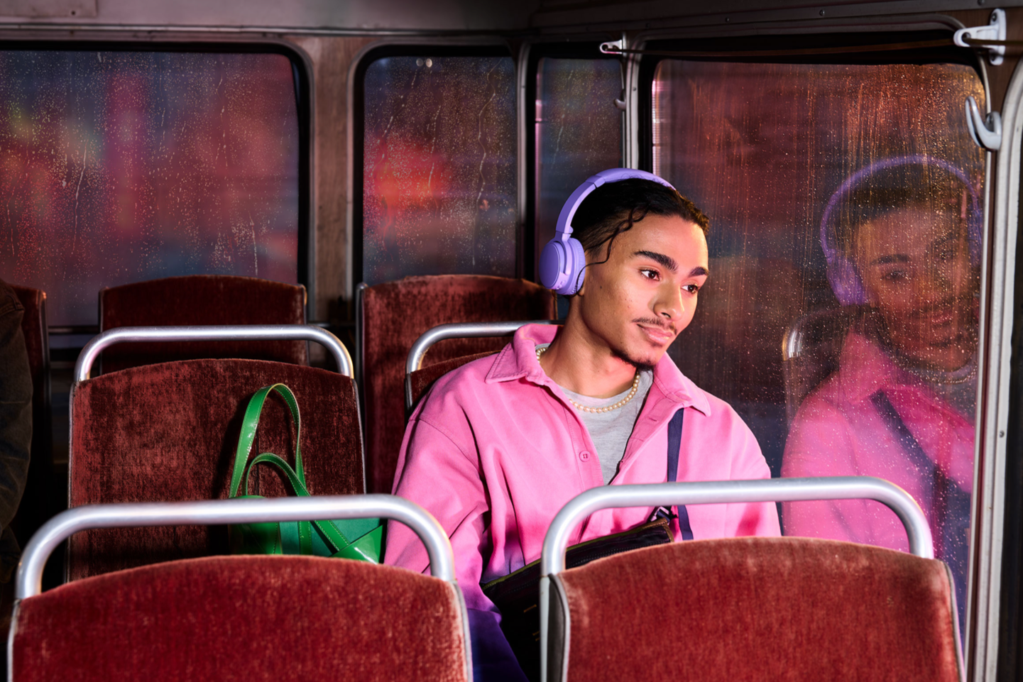 Ragazzo seduto su un autobus che indossa della cuffie.