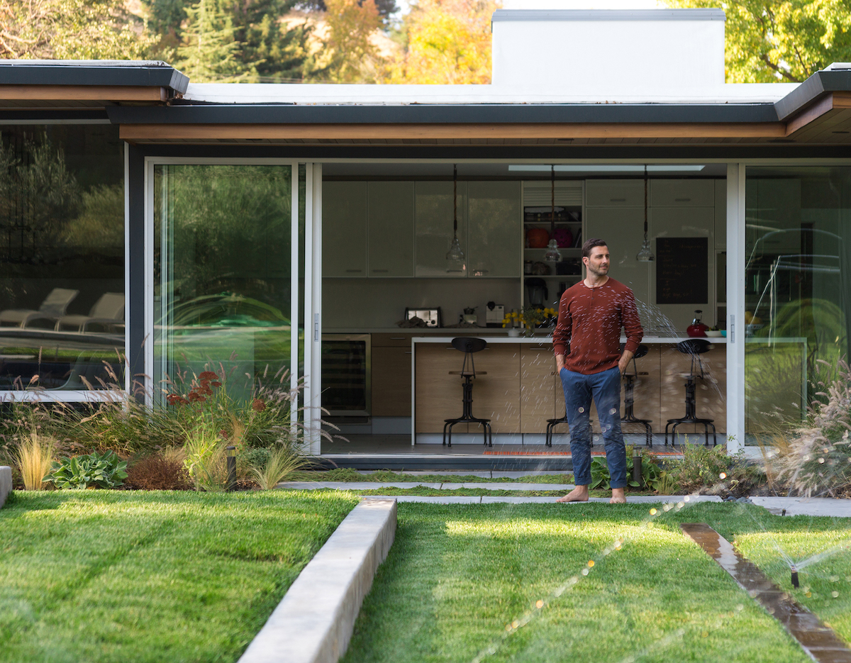 Man standing in yard admiring his working sprinkler system