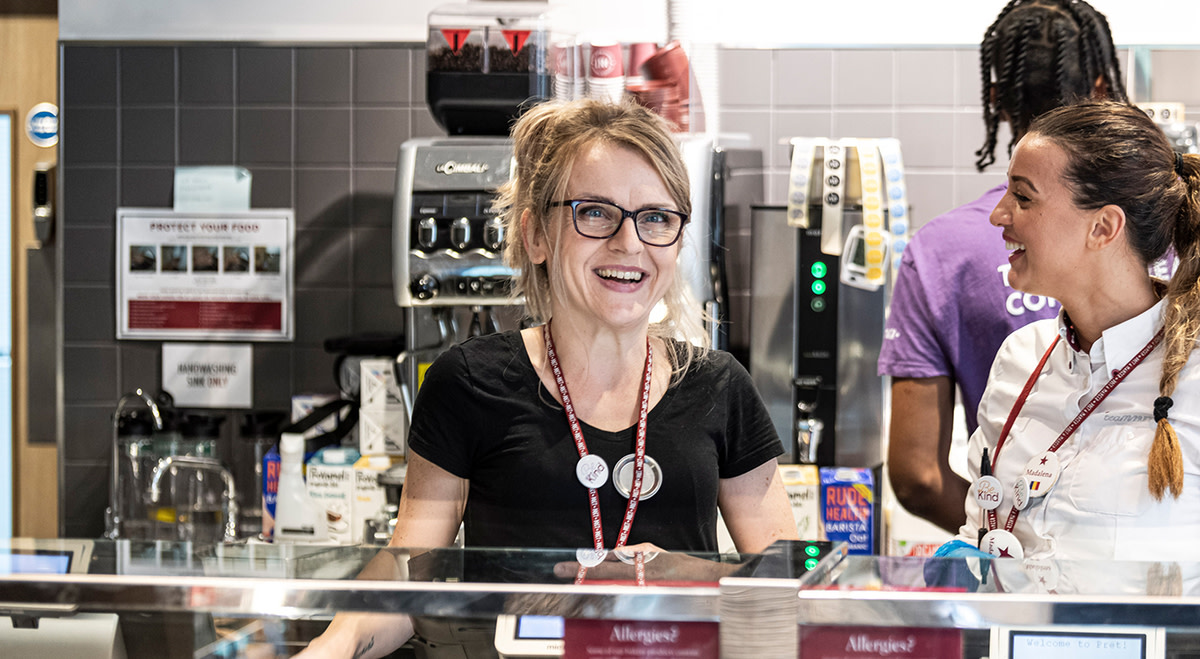 2 baristas behind the counter smiling