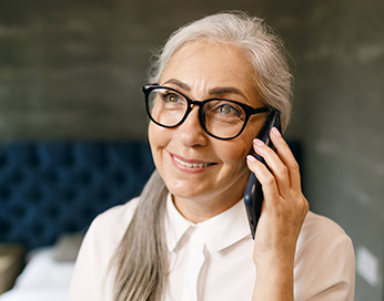 Lächelnde Frau mittleren Alters mit Brille hält Smartphone