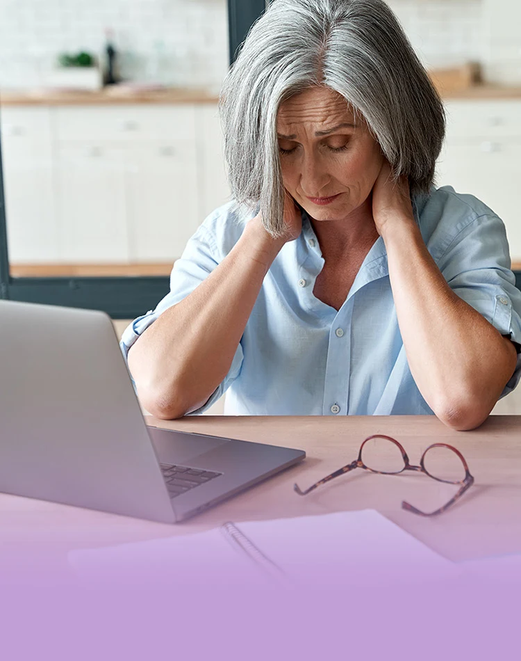 Eine besorgte grauhaarig Frau mittleren Alters sitzt am Laptop