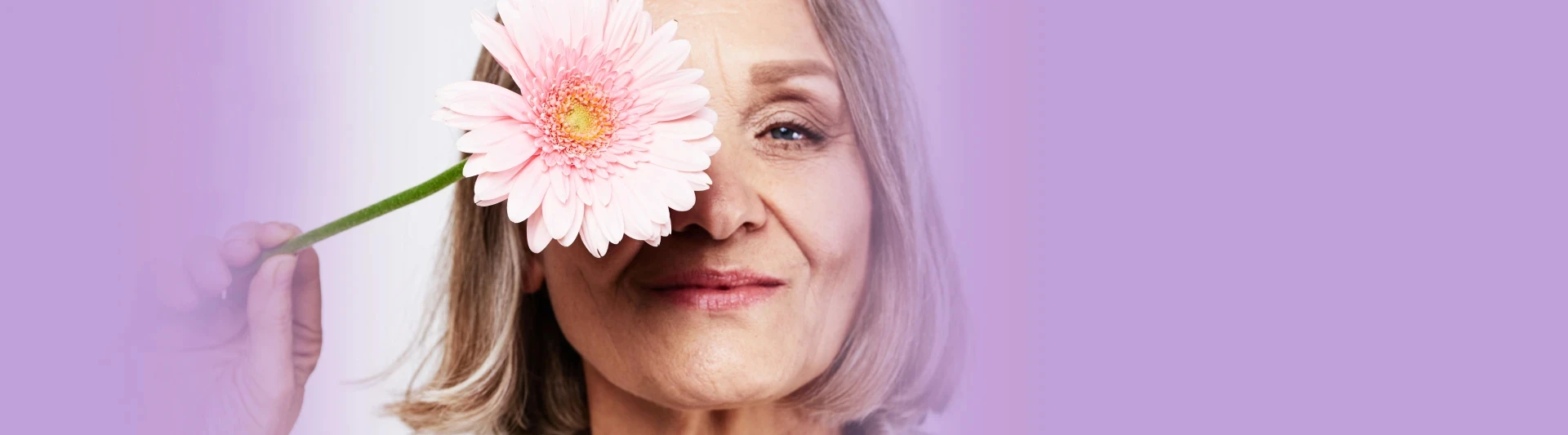 Eine Frau mittleren Alters bedeckt ihr Auge mit rosa Blume