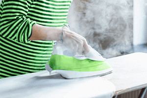 Person Steam Ironing White Cotton Cloth