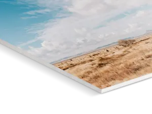 Foto-Druck auf Forex Nahaufnahme einer Ecke eines Direktdrucks auf Forex mit Wolken, die über eine hügelige Landschaft mit Bergen im Hintergrund ziehen.