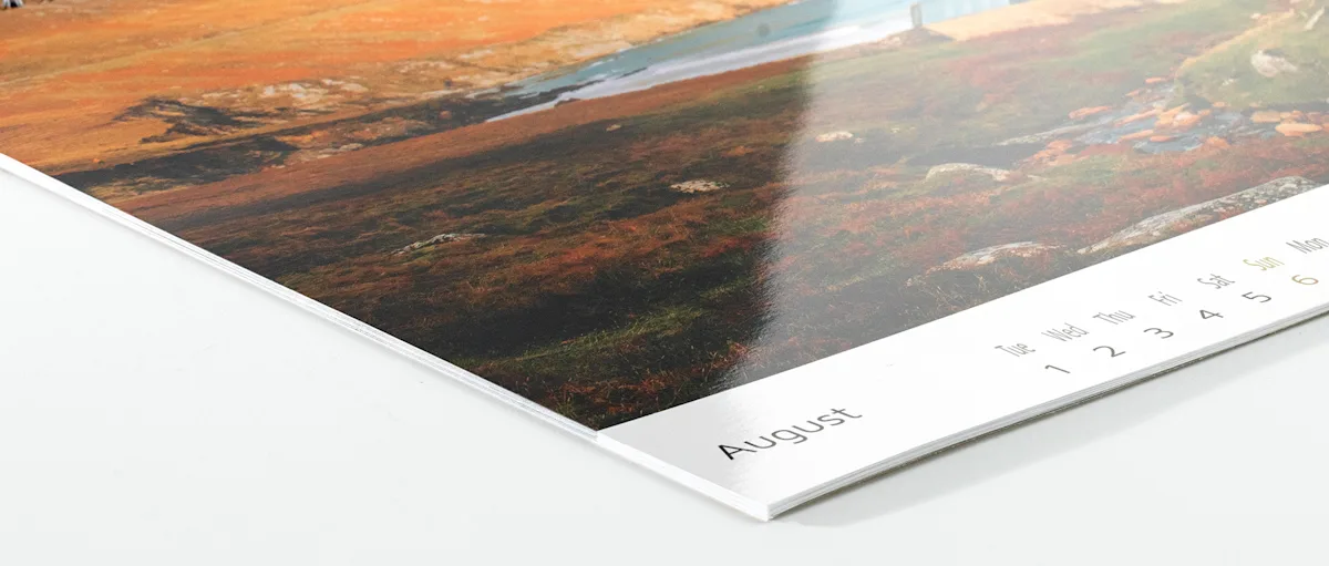 Photo Calendar Inkjet high gloss Close-up view of a calendar page showing August, with a partial landscape image visible above featuring autumn-colored terrain