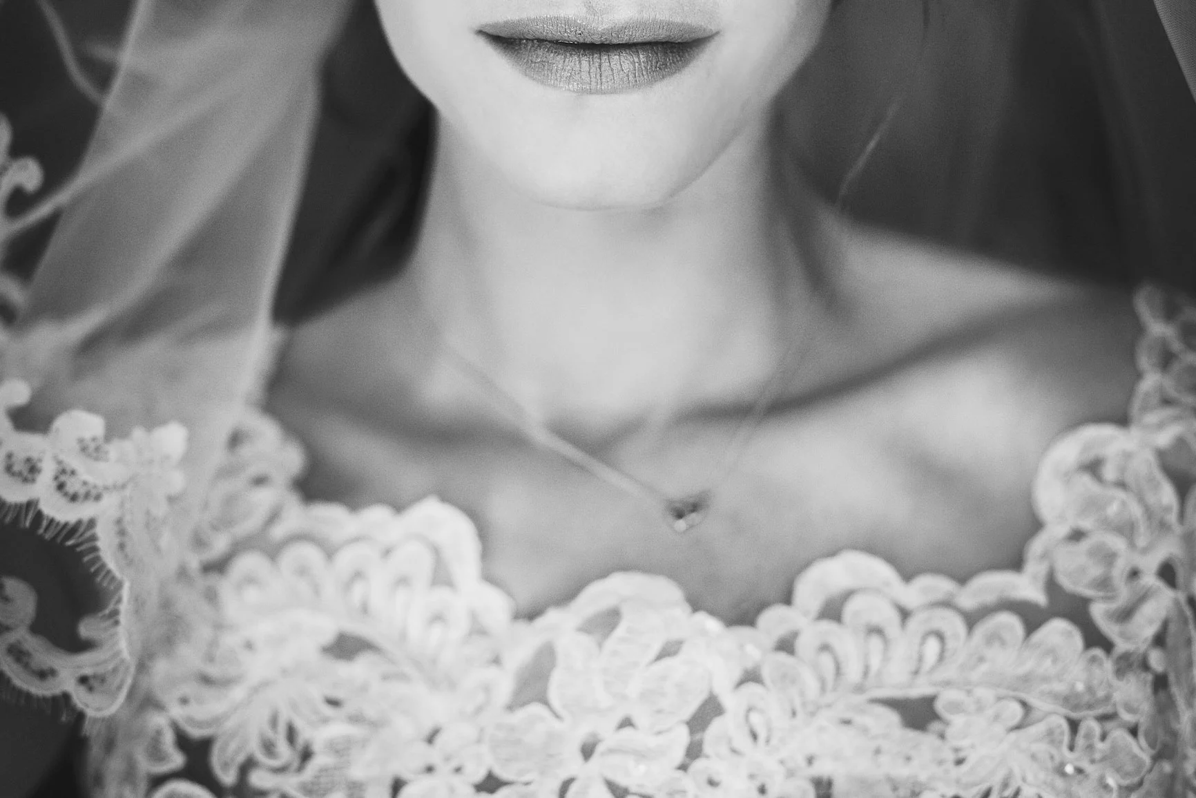 Black-and-white close-up of a wedding dress A black-and-white close-up of a wedding dress with a lace pattern, showing a woman's neck and lips.