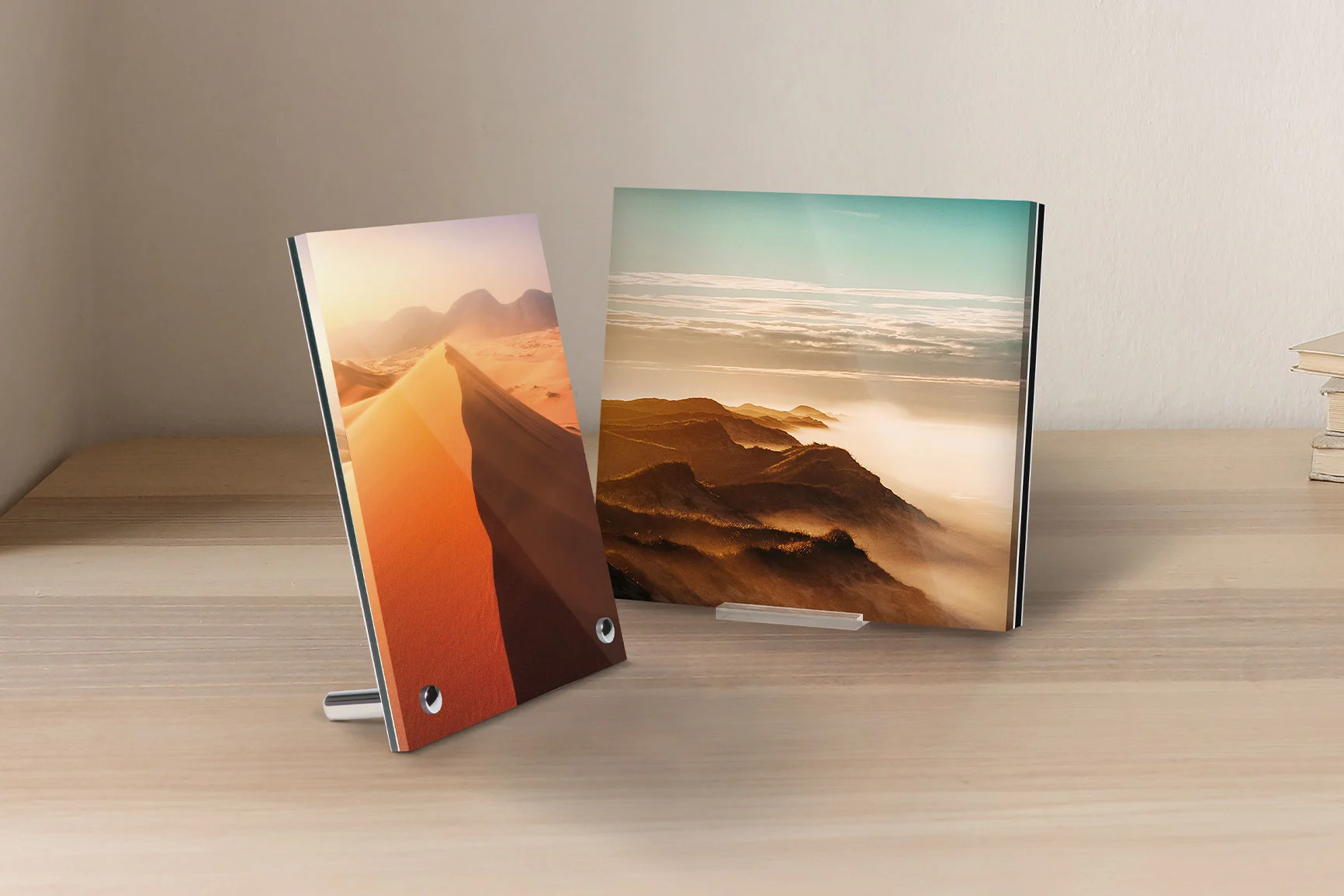 Two photo displays made of acrylic glass on a wooden table, one showing a sand dune, the other a mountain landscape. Two photo displays made of acrylic glass on a wooden table, one showing a sand dune, the other a mountain landscape.