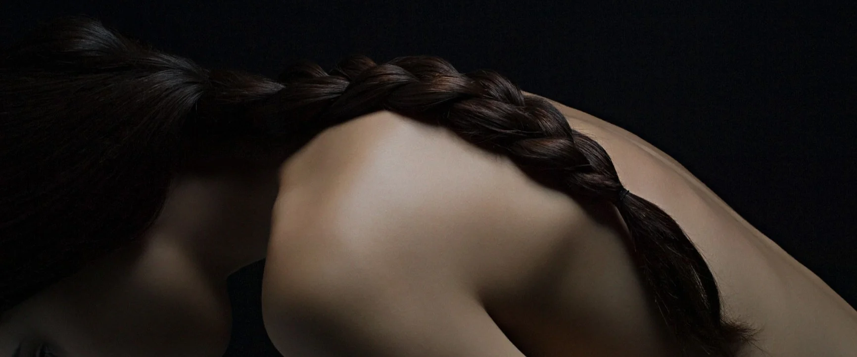 A close-up shot from the side of a woman with a braided strand of hair falling down her back.