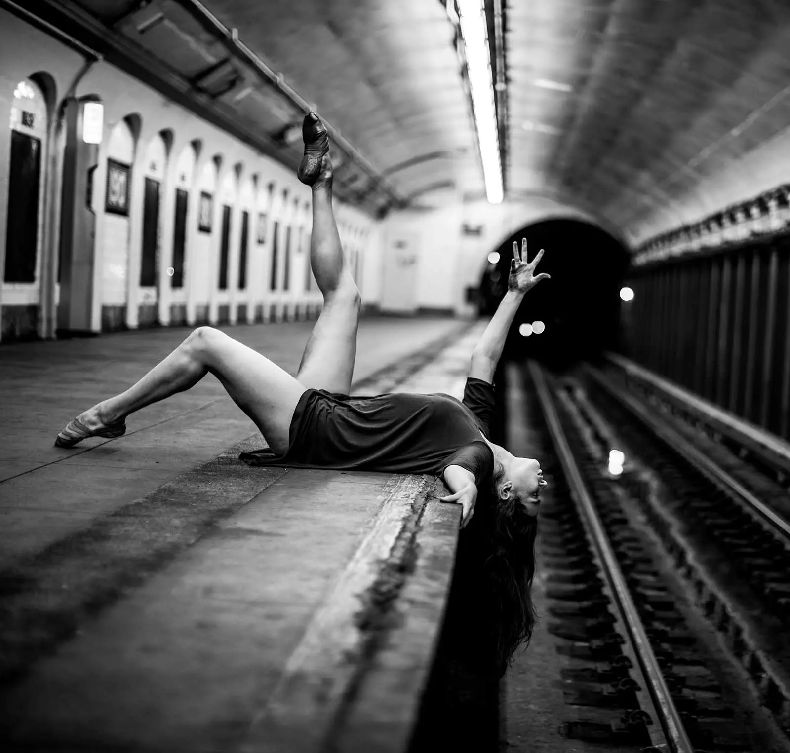 woman posing on the ground of a subway station.