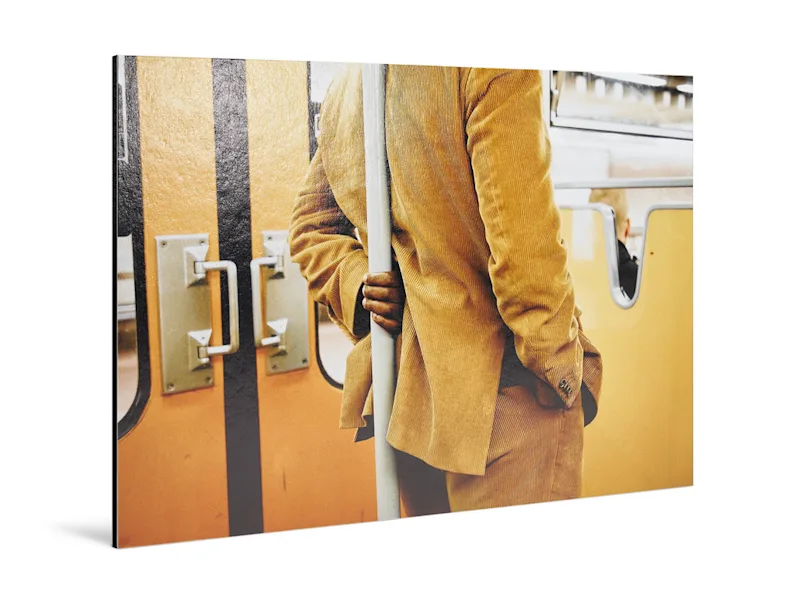 Fine Art Print auf Alu-Dibond Mann in beigem Anzug steht an einem U-Bahn-Pfosten.