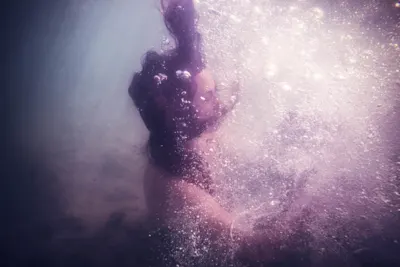 Martin Neuhof – Unterwasseraufnahme einer Person Bild von Martin Neuhof, Frau unter Wasser, Bild in violetten Farben.