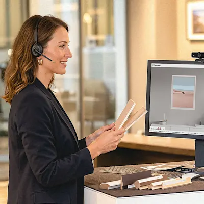 Expert neemt deel aan videogesprek aan een sta-bureau Vrouw met headset toont voorbeelden in videogesprek voor computer met productadvies.