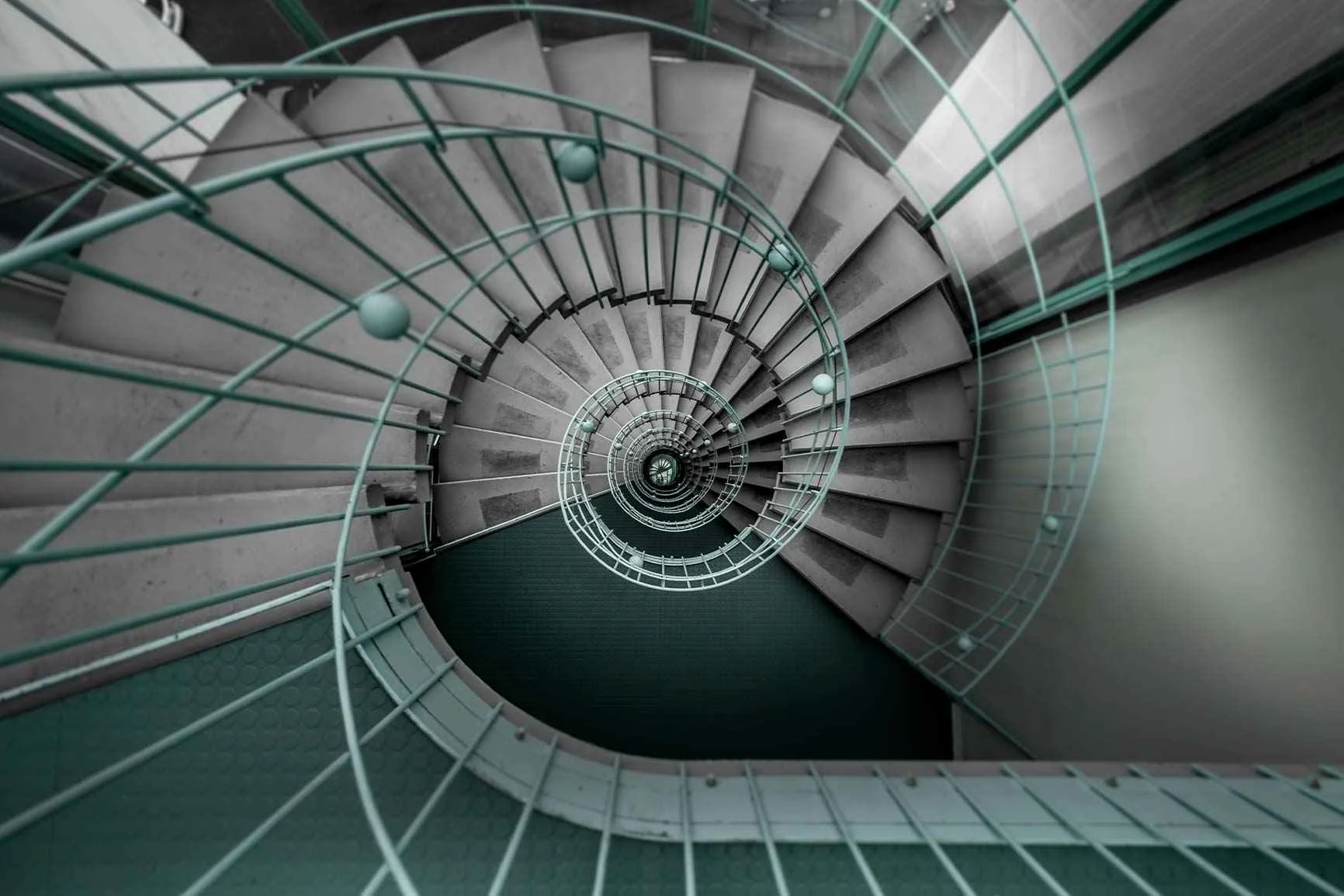 Bird's-eye view - Spiral staircase A spiral staircase with a metal railing, viewed from above.