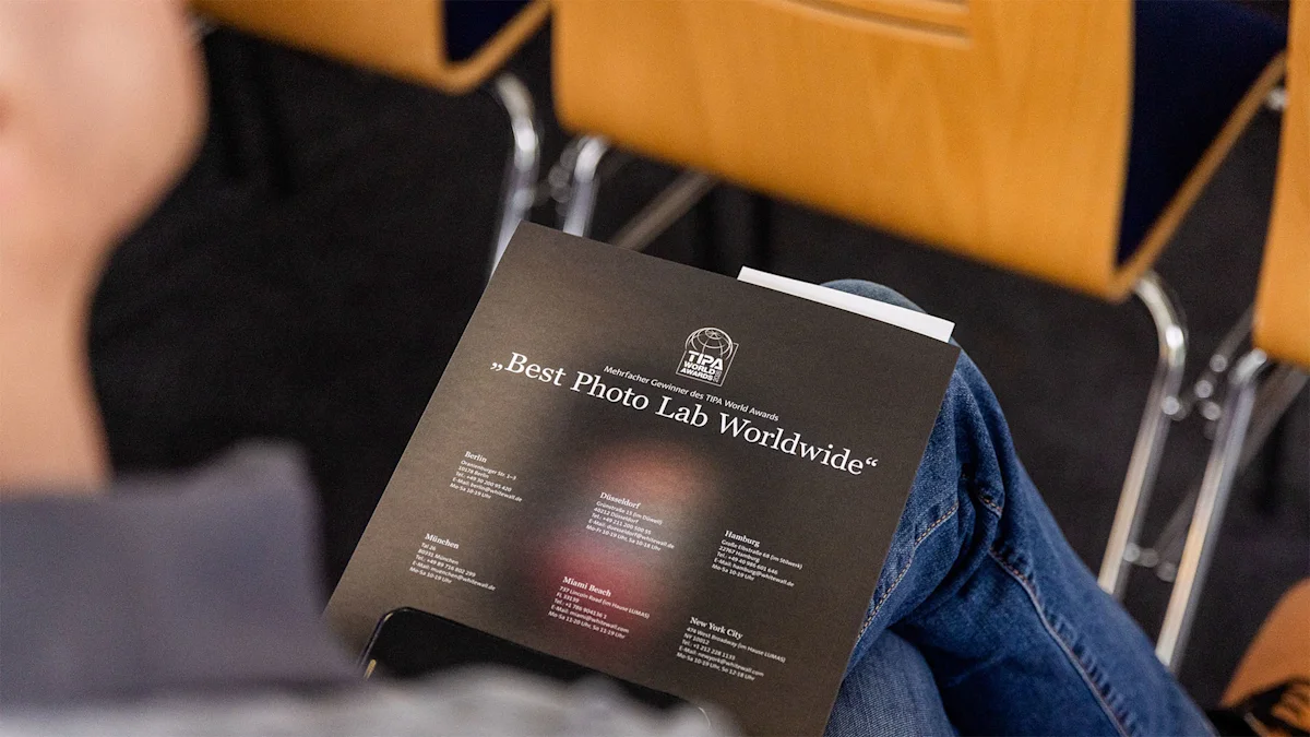 WhiteWall Expert Talk at the Zingst Photo Festival A person holds a dark brochure reading "Best Photo Lab Worldwide" with TIPA World Awards logo and location listings.