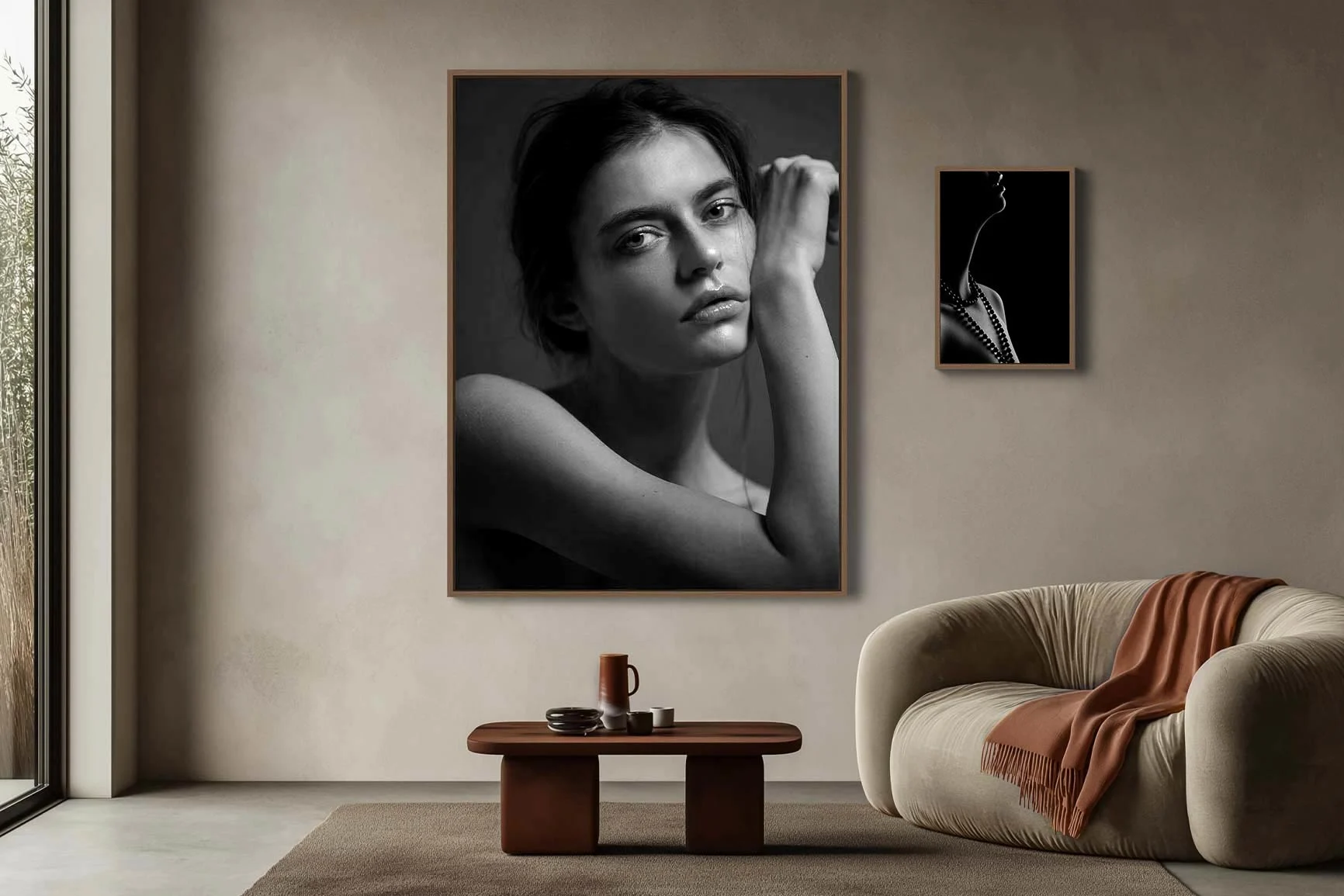 Living room with two black-and-white portrait photographs A living room with two black-and-white portrait photographs on the wall, a low wooden table with a cup, and an armchair with a blanket.