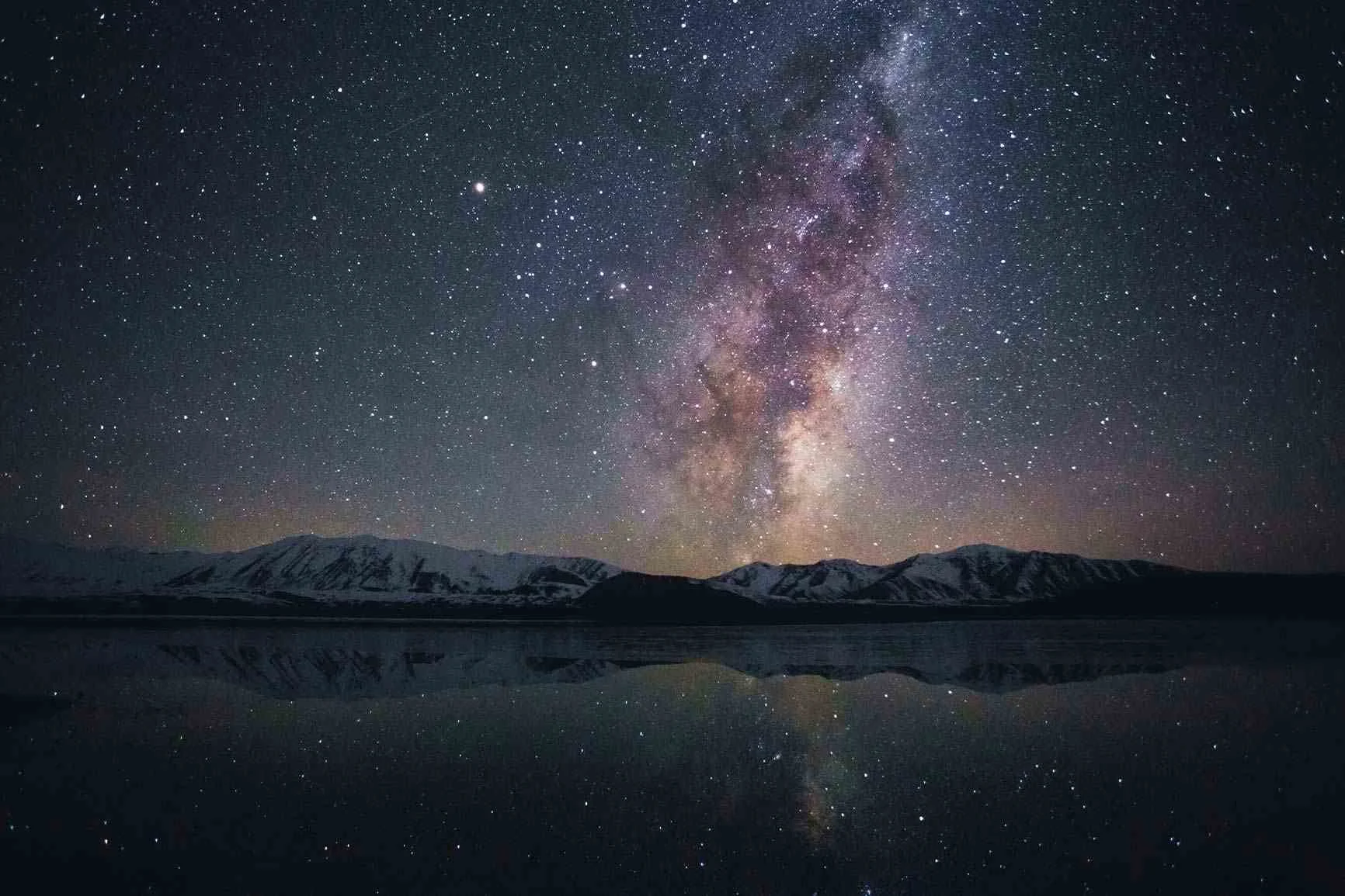 Starry sky with the milky way over mountains A starry sky with the Milky Way over snow-capped mountains, reflected in a calm lake.