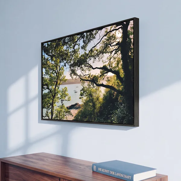 „WhiteWall Selected“ gerahmter Fotoabzug aus schwarzer Eiche Gerahmter Druck einer Küstenlandschaft mit Bäumen und Wasser, über einem Sideboard aufgehängt; daneben eine Nahaufnahme des Details des dunklen Holzrahmens.