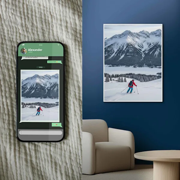 Comparison between smartphone photo and large-format wall art A split view: On the left, a smartphone lies on a textured fabric, displaying a chat with a winter sports photo (skier in front of a mountain panorama). On the right, the same motif is shown as a high-quality, large-format wall print in a white frame on a dark blue wall in a modern room.