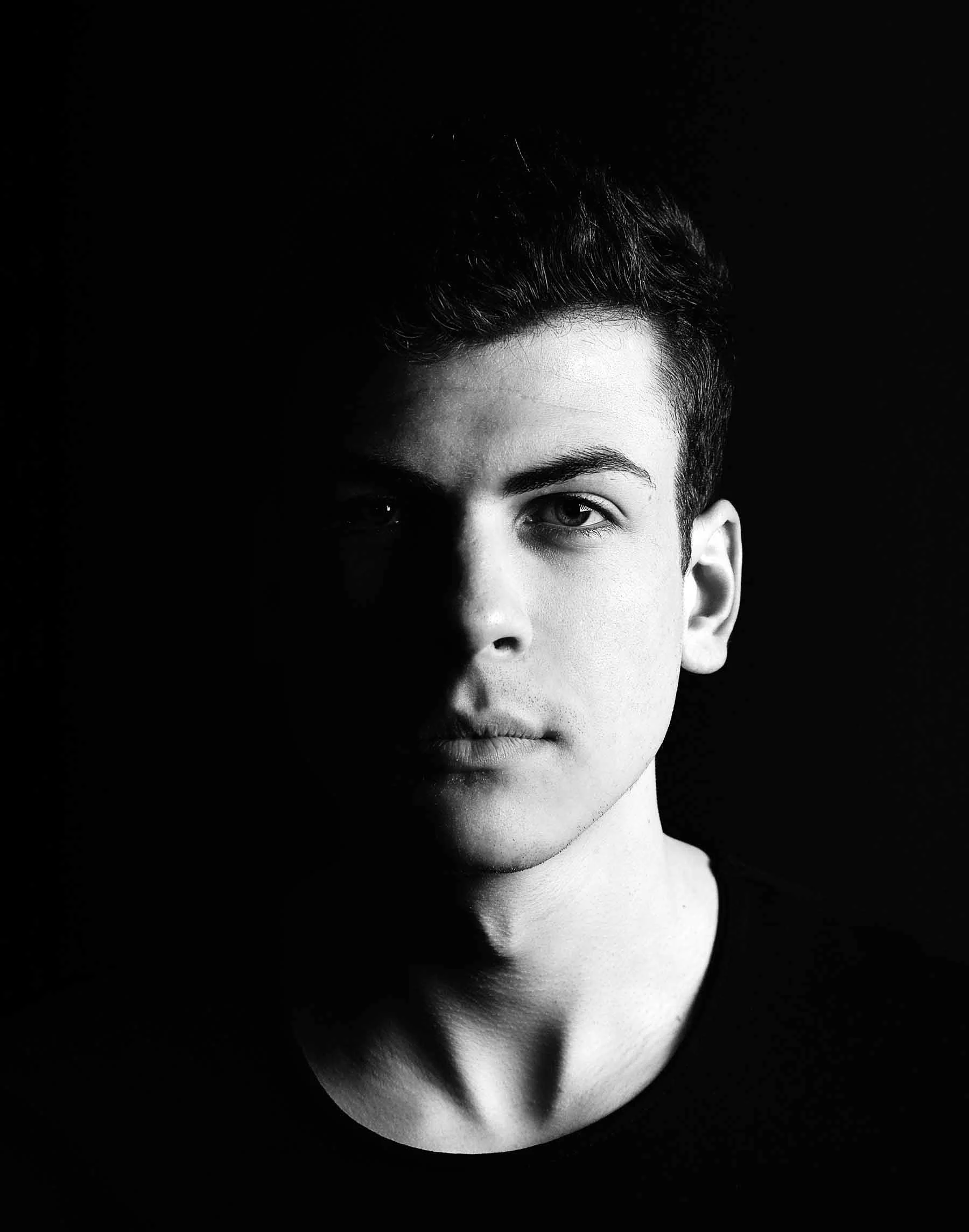 Retrato de un joven con cabello oscuro, con la mitad del rostro en sombra sobre un fondo negro. Retrato de un joven con cabello oscuro, con la mitad del rostro en sombra sobre un fondo negro.