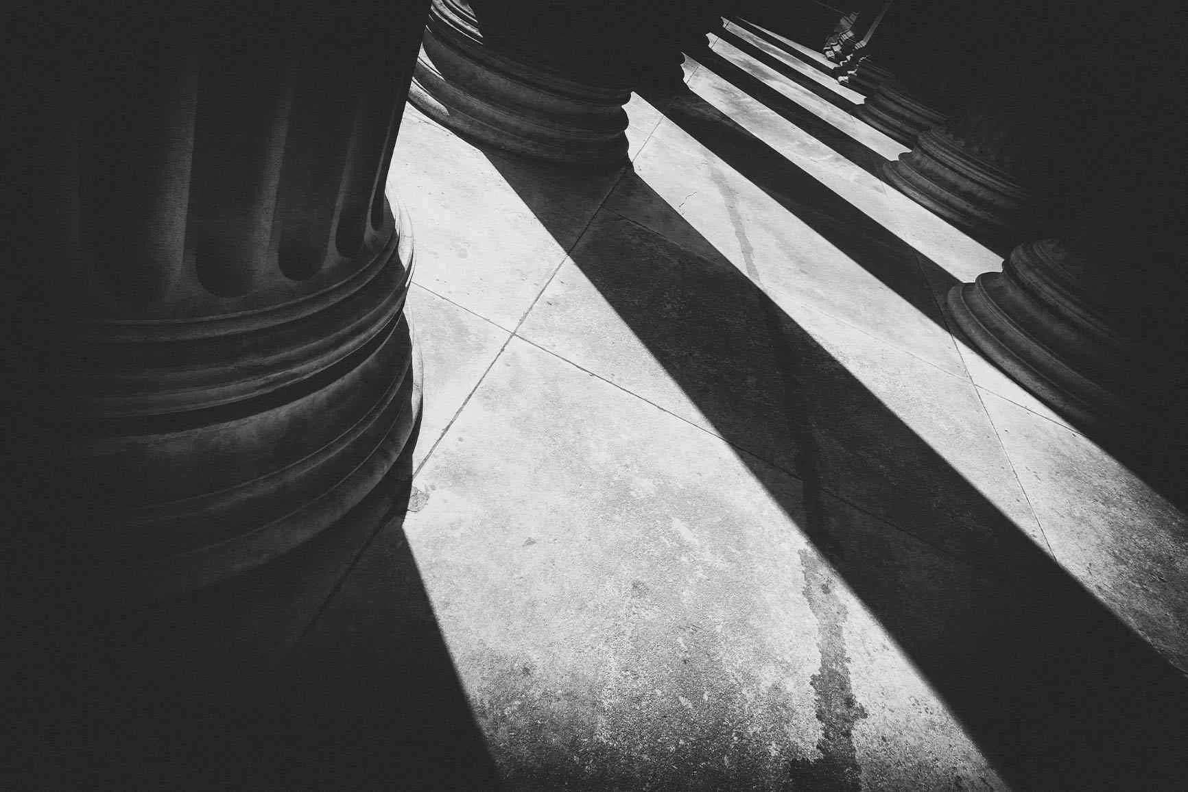 Black-and-white column base A column base casting long shadows on a black-and-white stone floor.