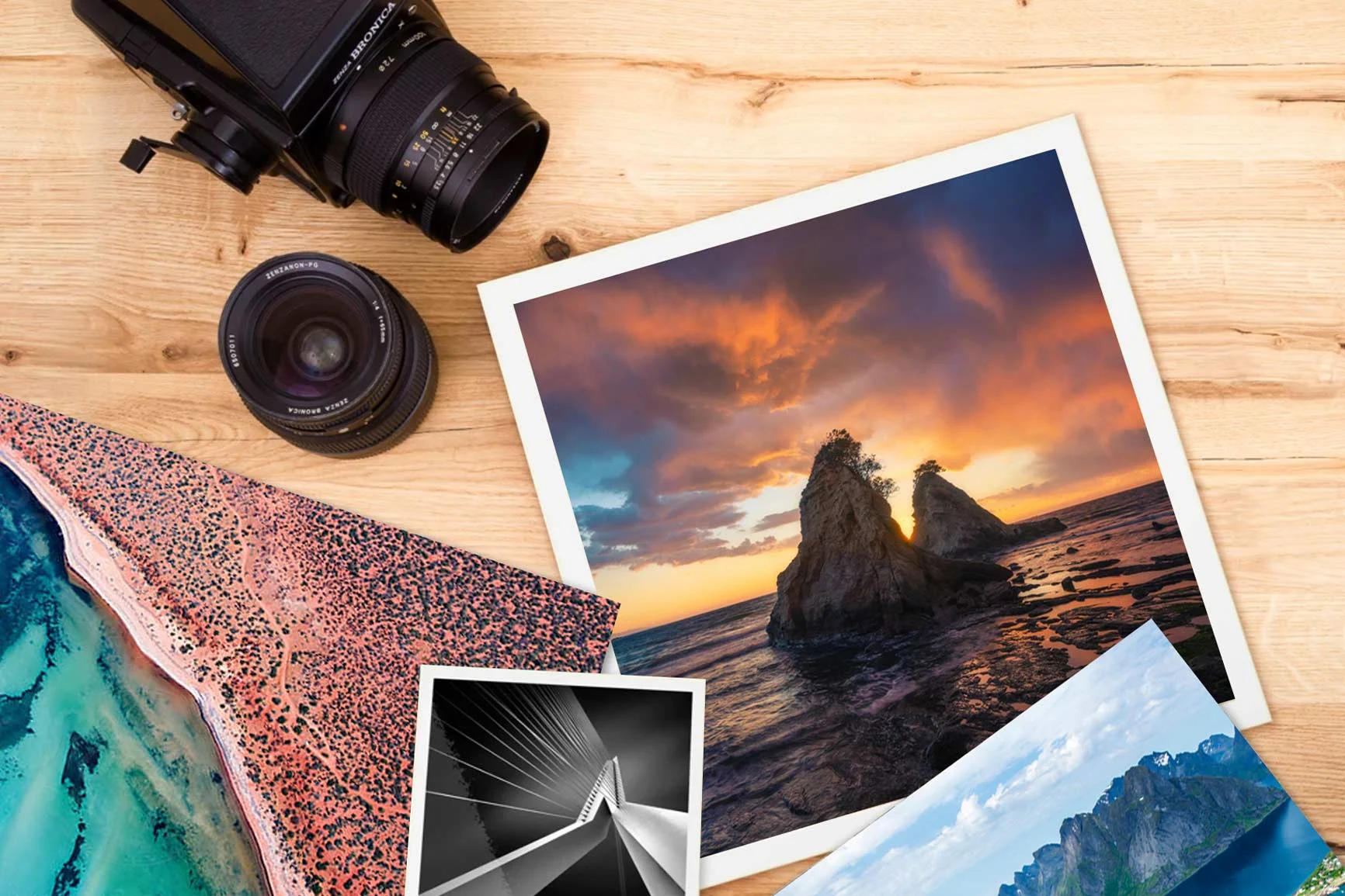 Fotografie di paesaggi e natura, accanto a macchina fotografica e obiettivo su tavolo di legno. Fotografie di paesaggi e natura, accanto a macchina fotografica e obiettivo su tavolo di legno.