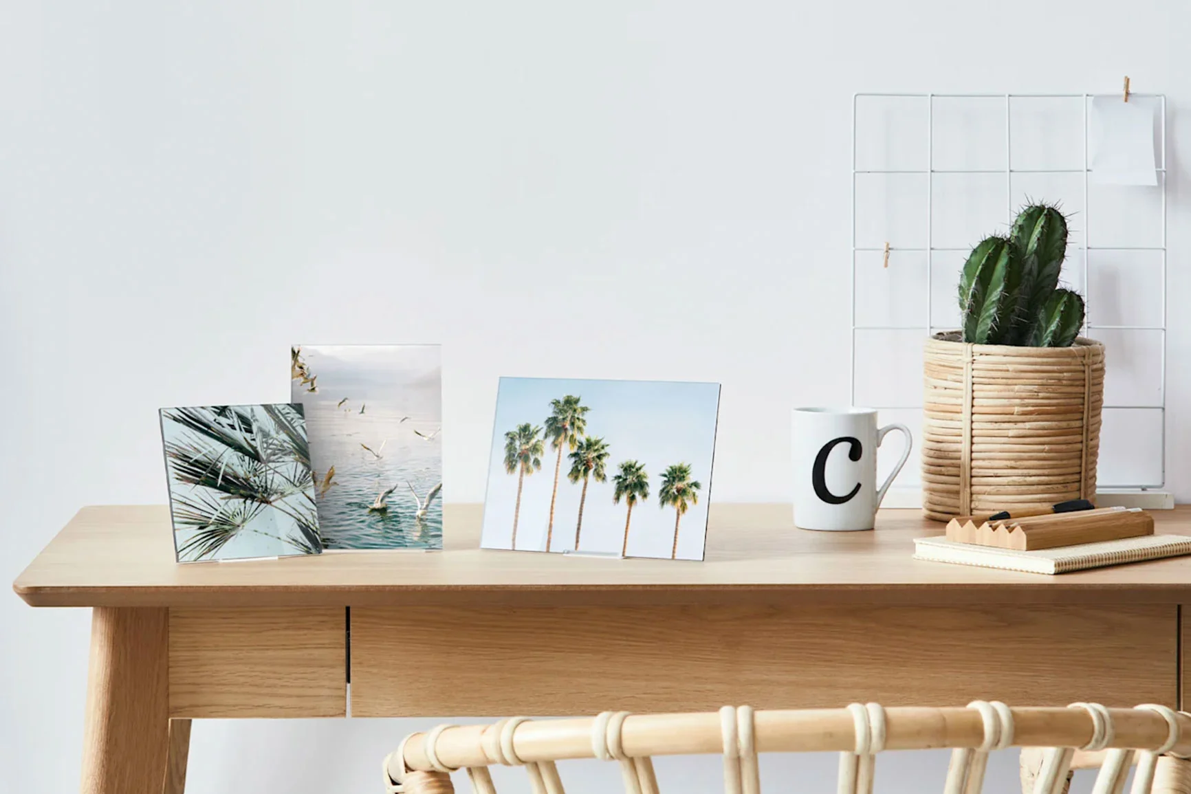 Three WhiteWall mini photo prints with palm tree motifs on a wooden table next to a cup and a cactus. Three WhiteWall mini photo prints with palm tree motifs on a wooden table next to a cup and a cactus.