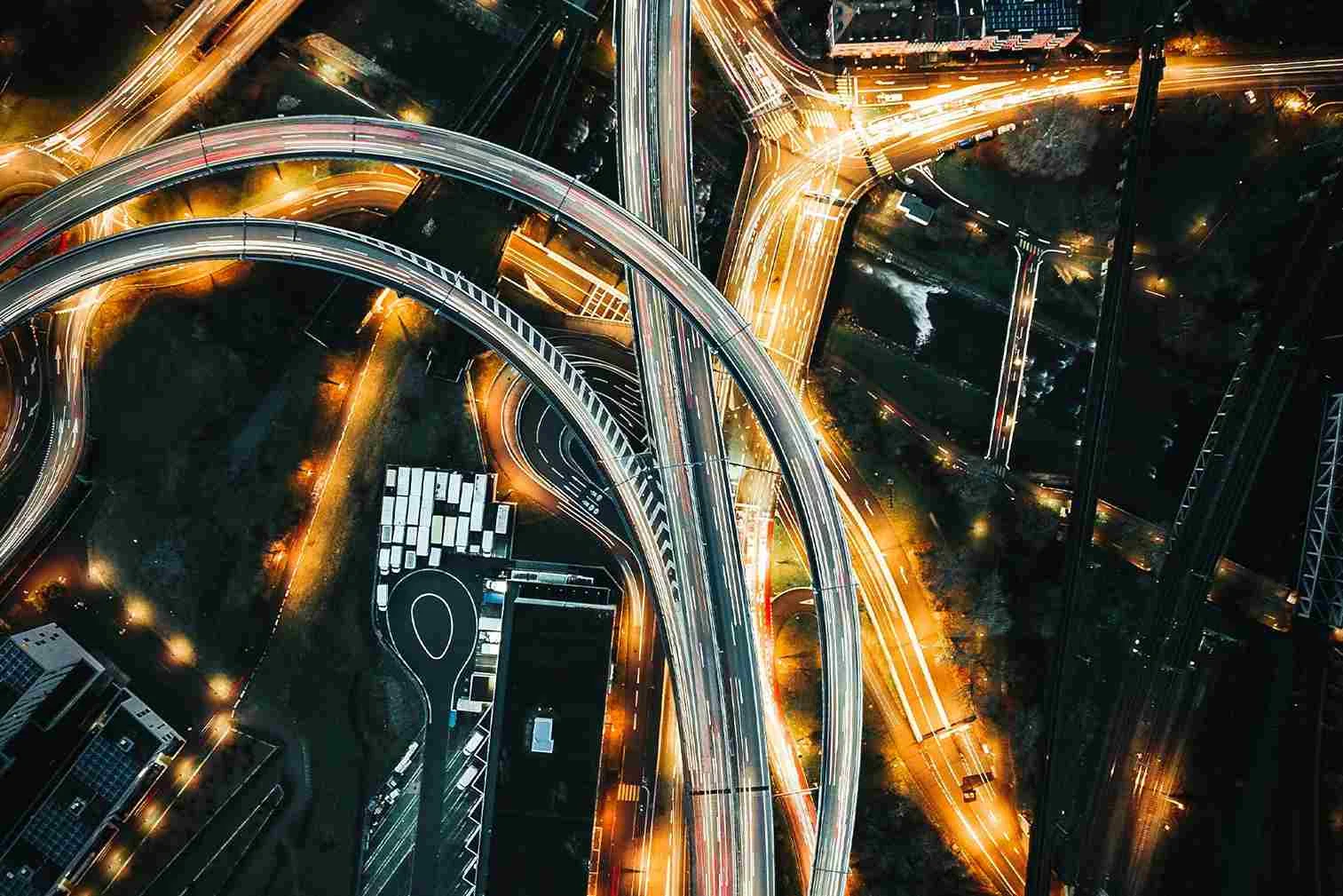 Aerial view of a highway interchange An aerial view of a multi-lane highway interchange at night, with illuminated roads and moving traffic.