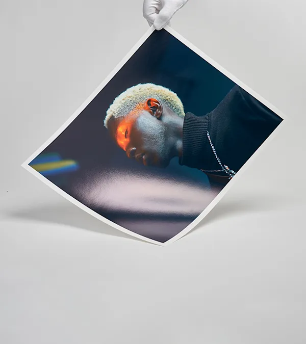 Eine behandschuhte Hand hält eine Porträtfotografie als Fine Art Print.