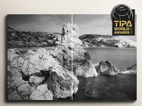Best Photo Lab - TIPA 2024 Paysage côtier en noir et blanc avec des formations rocheuses accidentées émergeant des eaux calmes, avec superposition du logo TIPA World Awards