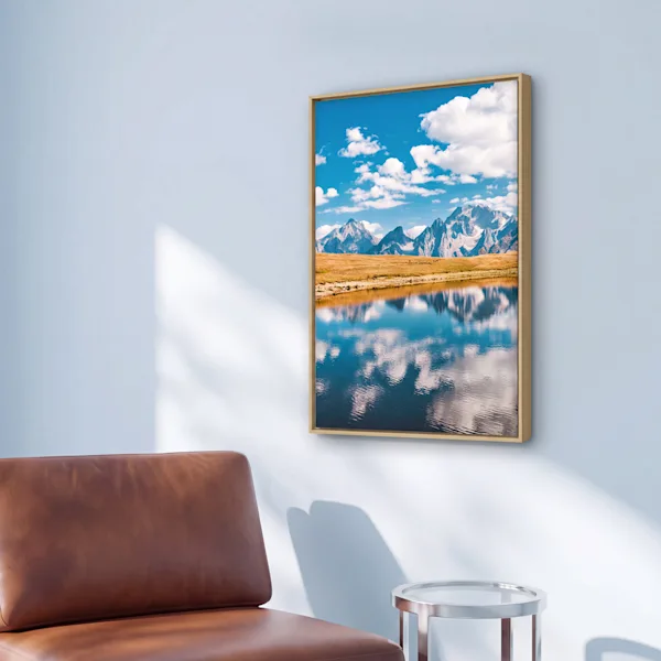 „WhiteWall Selected“ gerahmter Fotoabzug aus Natur-Eiche Ein gerahmter Druck einer Berglandschaft mit Spiegelung im See hängt über einem braunen Ledersessel; zudem ist eine Nahaufnahme des Holzrahmens zu sehen.