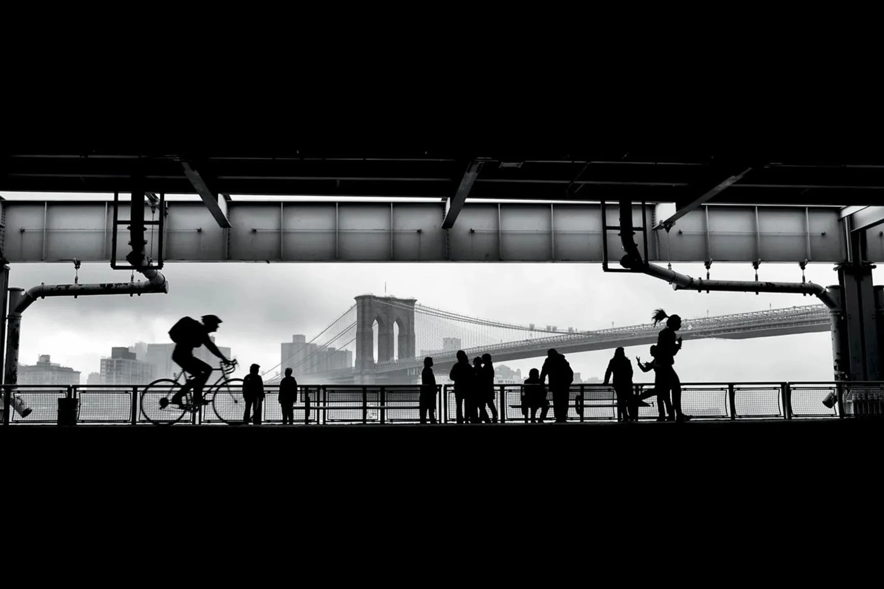 Black-and-white Brooklyn Bridge Black-and-white silhouettes of people and a cyclist in front of the Brooklyn Bridge in New York.