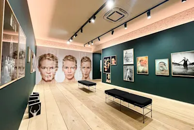 Joachim Baldauf - exhibition display Gallery with fashion photography on dark walls, light wooden floor and black benches.