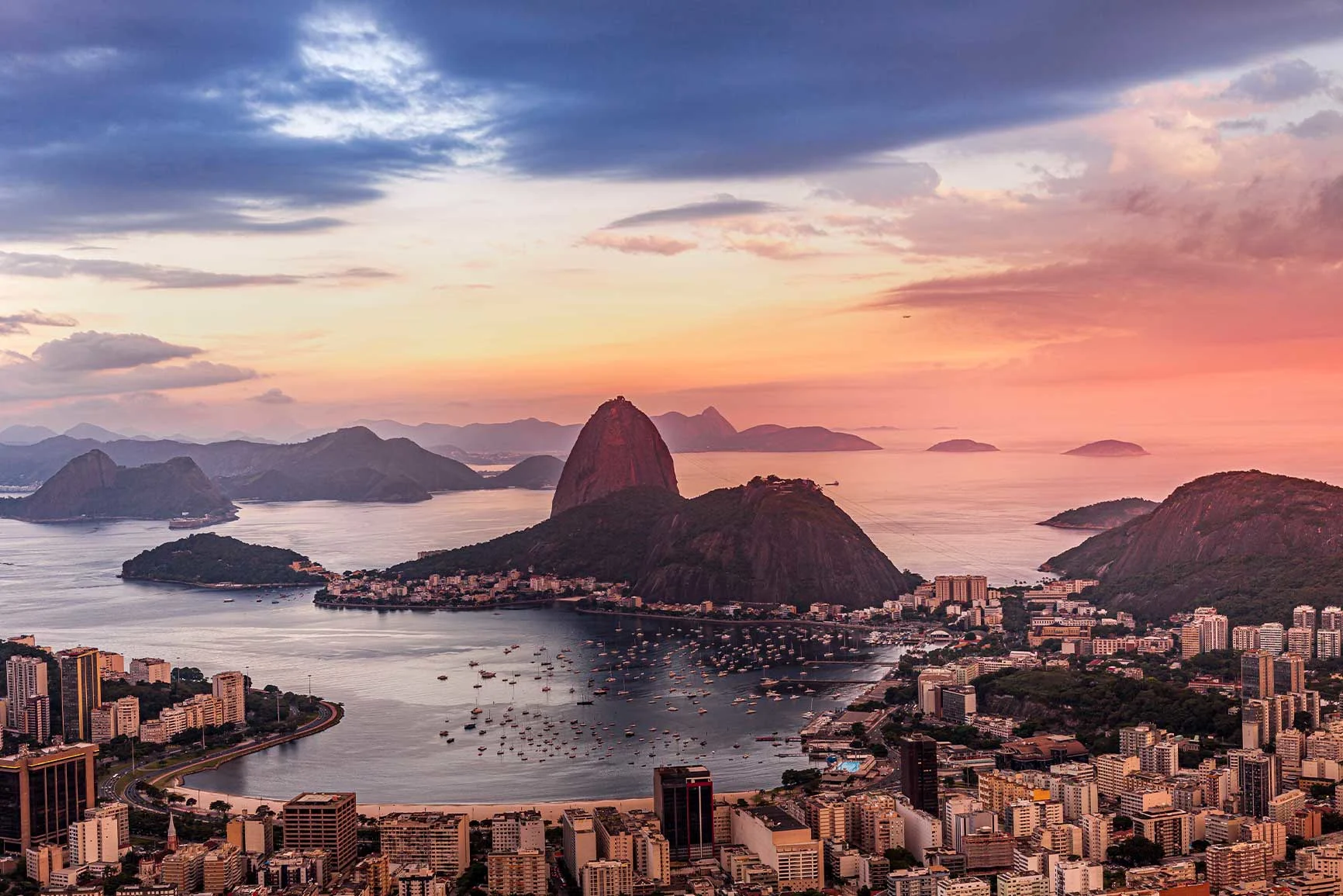 Vista sul Pan di Zucchero e sulla baia di Rio de Janeiro al tramonto, con gli edifici della città in primo piano. Vista sul Pan di Zucchero e sulla baia di Rio de Janeiro al tramonto, con gli edifici della città in primo piano.