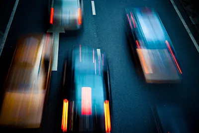 Several moving, blurry vehicles A bird's-eye view of a street with several moving, blurred vehicles.