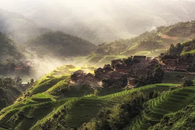 La lumière disponible en photographie 6 Des villages entre des rizières en terrasses verdoyantes. La lumière du soleil perce la brume au-dessus des collines.