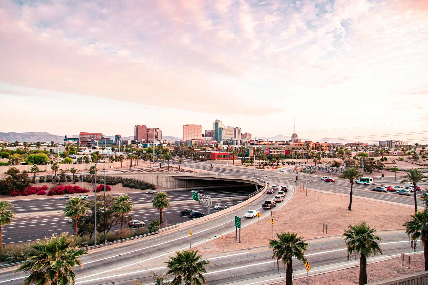 Cityscape in natural light A cityscape featuring a highway on-ramp, several vehicles, and palm trees in natural light.