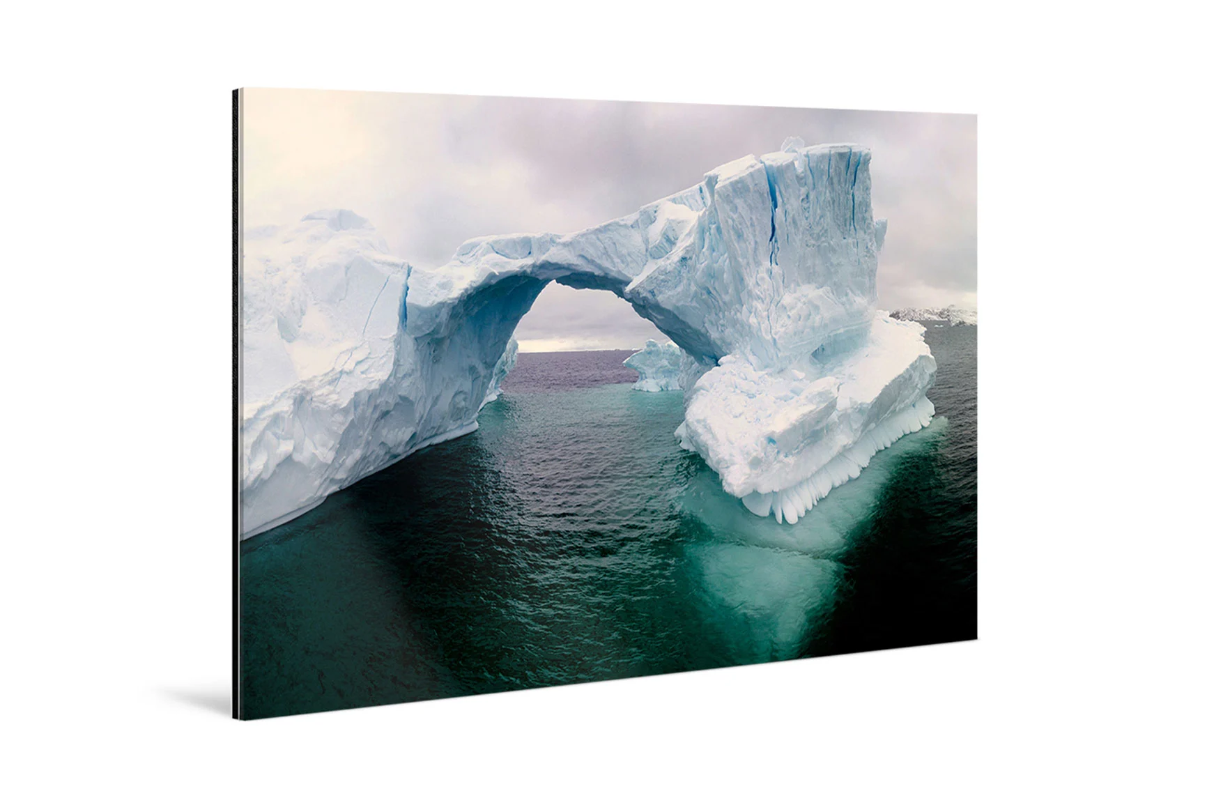 Fine Art pigment print mounted behind acrylic glass A Fine Art pigment print mounted behind acrylic glass depicts a natural ice bridge over water with a cloudy sky in the background.