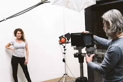 Studio photo shoot: photographer and model A photographer with a camera on a tripod in front of a model in a photo studio.