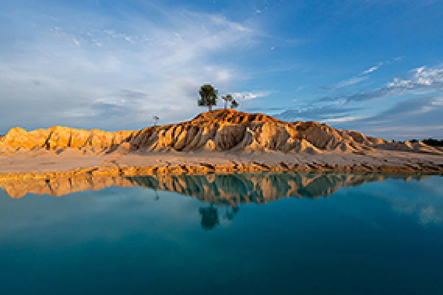 Dune de sable avec quelques arbres, se reflétant dans l'eau calme sous un ciel bleu, floue et pixélisée. Dune de sable avec quelques arbres, se reflétant dans l'eau calme sous un ciel bleu, floue et pixélisée.