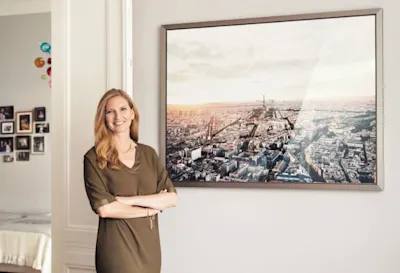 Susanne Kaiser - Portrait Portait von Susanne Kaiser neben gerahmten Foto von der Pariser Innenstadt.