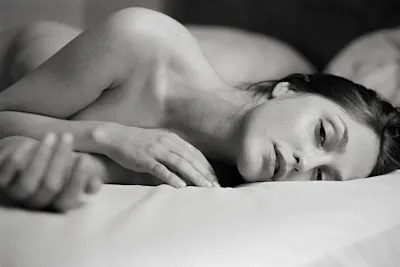 LP | Magazin | Inspiration | Product Grid Section | Auch interessant | Aktfotografie | Grid #5 A woman lying on a bed, resting her head on a pillow with her arm stretched out.
