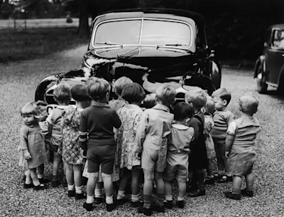 Kinder vor altem Auto Gruppe von Kleinkindern in Vintage-Kleidung steht vor einem alten Auto, Schwarz-Weiß-Fotografie.