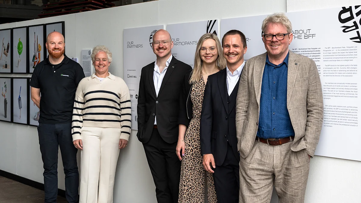 WhiteWall x BFF Förderpreis 2026 Five smiling professionals pose together at a BFF photography exhibition, standing in front of informational display panels.